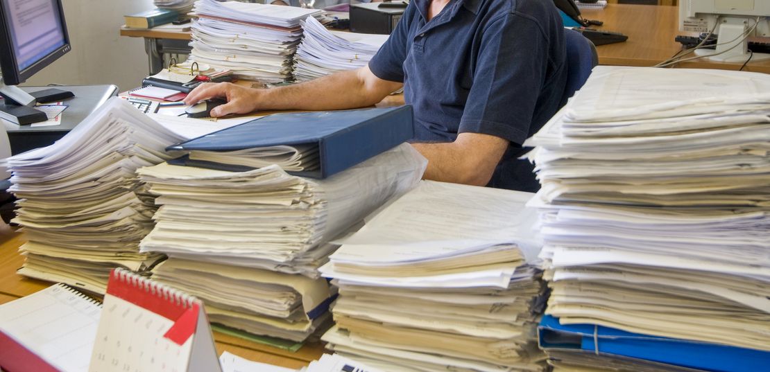 Illustrazzjoni ta’ tim jitħabat ma’ munzelli ta’ dokumenti tal-offerti